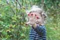 Exhilarated two years old blonde girl showing red garden raspberry fruits