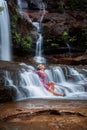 Exhilaration in mountain waterfall, female sitting in flowing ca