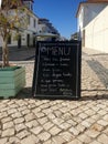 An existential menu put across the southern white paved street in Portugal recites classics