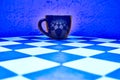 Dark cup on blue chess board and blue abstract background Royalty Free Stock Photo