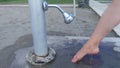 At the exit from the city beach, a water column is located on the wooden deck. A woman washes her feet from the sand under the jet