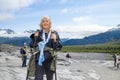 Exit Glacier Alaska USA Senior lady hiking on rough terrain using hiking sticks - Coat tied around waist - our tourists Royalty Free Stock Photo