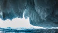 The exit from the ice cave is surrounded by rows of blue shiny icicles