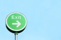 Exit round green sign against blank blue sky with direction arrow in car park Royalty Free Stock Photo