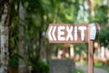 Exit sign on a wooden plank, old, vintage, left direction sign, against the background of green trees in the hotel