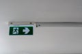 Exit signs, fire exits and arrows pointing the way on the ceiling of building corridors