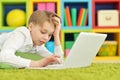 Exited boy using laptop while lying on floor