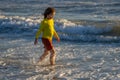 Exited carefree little boy running on wet coast near waving sea on sunny summer day. Child running at summer beach Royalty Free Stock Photo