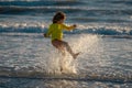 Exited carefree little boy running on wet coast near waving sea on sunny summer day. Child splashing in sea. Kid play Royalty Free Stock Photo