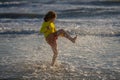 Exited carefree little boy running on wet coast near waving sea on sunny summer day. Kid running at summer beach Royalty Free Stock Photo