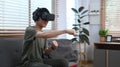 Exited man playing video game or watching movie in virtual reality headset, sitting on couch in cozy home Royalty Free Stock Photo