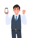 Exited man in vest suit showing mobile, cell or smartphone and gesturing raised arm fist sign. Person celebrating success. Royalty Free Stock Photo