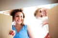 Exited mother and cute little daughter looking inside carton box Royalty Free Stock Photo