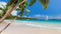 Sunny beach with coconut palms and a sailing boat in the turquoise sea on Paradise island. Royalty Free Stock Photo