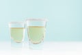 Exotic coctail with sour green lime in shot glass with sugar rim on soft light mint color background and white wood board.