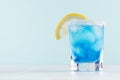 Exotic cold shot glass cocktail with blue curacao, ice cubes, salt rim, lemon slice on soft light mint color background. Royalty Free Stock Photo