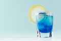 Exotic cold shot glass cocktail with yellow lemon slice, blue curacao, ice cubes, salt rim on soft light mint color background. Royalty Free Stock Photo