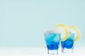 Exotic cold shot glass cocktail with yellow lemon slice, blue curacao, ice cubes, salt rim on soft light mint color background. Royalty Free Stock Photo