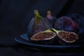 Exotic fig fruits in a blue plate on black background, close up, isolated, still life photography Royalty Free Stock Photo