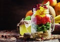 Exotic fruit salad with banana, kiwi, grapefruit, mango, cranberry and lemon juice and honey, served in a glass jar. Vintage wood