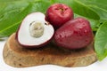 Exotic fruit Syzygium malaccense with leaves and one cut in wood background