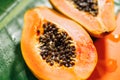 Exotic fruits background. Papaya orange fresh fruits on tropical leaf green background. Halved fresh organic Papayas