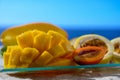 Exotic fruits, fresh ripe sweet yellow mango and passion fruits served on glass plate with blue seaview background Royalty Free Stock Photo