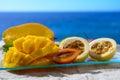 Exotic fruits, fresh ripe sweet yellow mango and passion fruits served on glass plate with blue seaview background Royalty Free Stock Photo