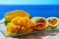 Exotic fruits, fresh ripe sweet yellow mango and passion fruits served on glass plate with blue seaview background Royalty Free Stock Photo