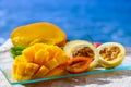 Exotic fruits, fresh ripe sweet yellow mango and passion fruits served on glass plate with blue seaview background Royalty Free Stock Photo
