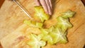 Exotic fruits on the table. 4k, Female hands cut a carambola with a knife on a cutting board, Slow motion