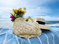 woman straw hat and handbag with wild flowers bouquet on blue beach towel blue cloudy sky nature summer landscape concept Royalty Free Stock Photo