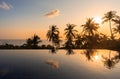 Exotic landscape view with palm trees reflected in surface of water in pool during orange sunset Royalty Free Stock Photo