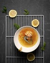 Exotic noodle and mussel soup and lemon slices. Top view of white bowl on black background. Spicy oriental dish