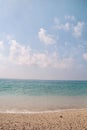 Exotic sandy beach, tropical mediterranean sea with waves and sea foam, blue sky and clouds. Natural environment, landscape. Royalty Free Stock Photo