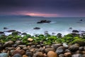 Nature Seascape with Rocks Covered by Green Mosses, Blurred Waves and Dark Cloudy Sky