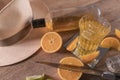 An exotic shot of vodka served in a glass with slices of ripe orange next to a straw hat and a knife on a wooden table Royalty Free Stock Photo