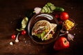 Exotic still slife with stuffed pita and fresh vegetables over wooden background, selective focus.