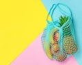 Exotic summer fruits in net bag on colorful background. Top view, copy space. Zero waste concept Royalty Free Stock Photo