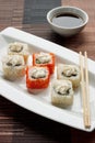 Exotically japanese seafood, roll and chopstick are lying on a white plate. Soy souce.