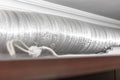 Expandable metallic aluminium corrugated air-conditioning ventilation pipe in kitchen connecting a cooker hood and a ventilation