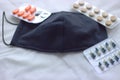 An expanded black protective mask lies on fabric napkins next to tablets and an antiseptic. Fighting COVID-19 Royalty Free Stock Photo