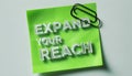 Expanding Your Reach A Bold White PostIt Note Motivational Message Against a Light Grey Background Royalty Free Stock Photo