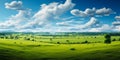 Expansive lush green field under a vibrant blue sky with fluffy white clouds surrounded by a line of trees on the horizon Royalty Free Stock Photo