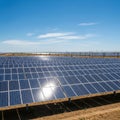 Vast solar farm under bright blue sky with wispy clouds reflecting sunlight on panels Royalty Free Stock Photo