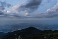 An expansive view from a mountaintop overlooking a city below, with a dramatic sky full of clouds. The lights of the city contrast Royalty Free Stock Photo