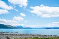 Expansive views turquoise water of Lake Tekapo with snow-capped Southern Alps behind and tourists on rocky foreshore Royalty Free Stock Photo