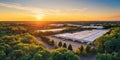 The expansive warehouse facility surrounded by vibrant green foliage at sunset. AI generated image Royalty Free Stock Photo