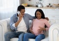 Expectant black woman having prenatal contractions, her boyfriend reaching doctor on smartphone from home Royalty Free Stock Photo