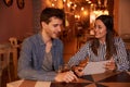 Expectant millenial couple sitting in restaurant